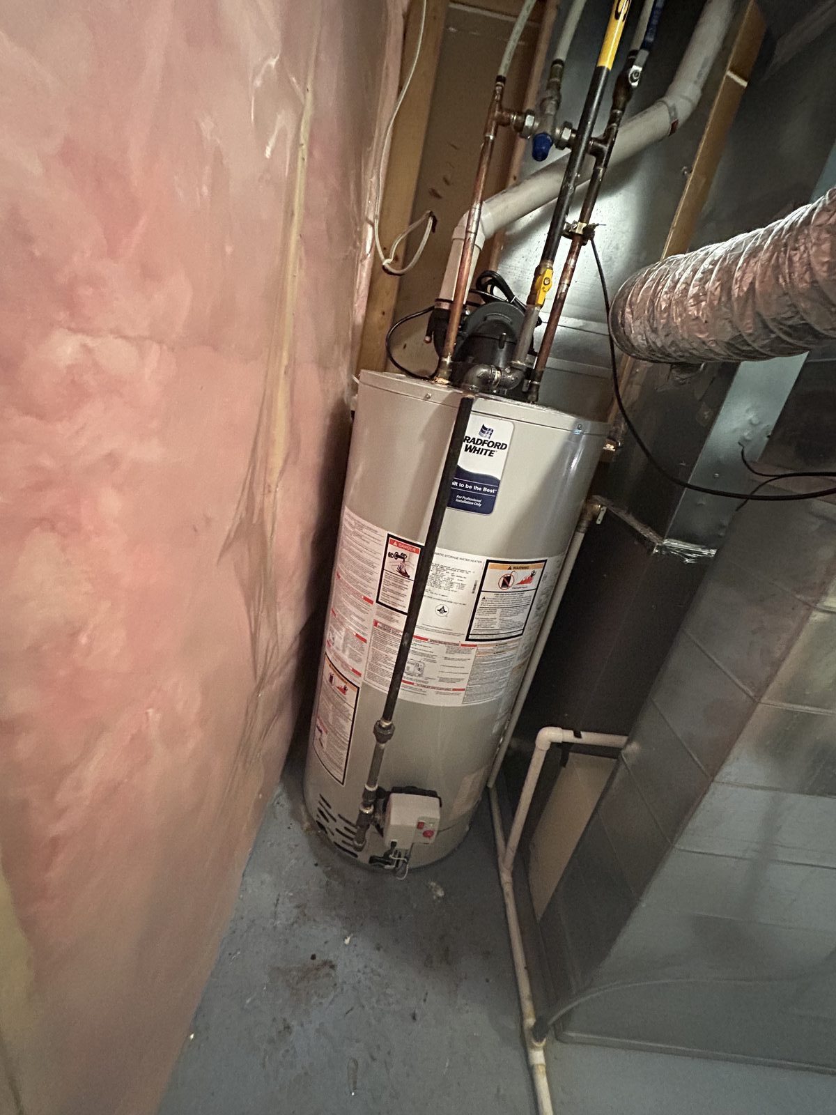 Bradford White power-vent gas water heater with PVC vent piping, copper water lines, and gas connection